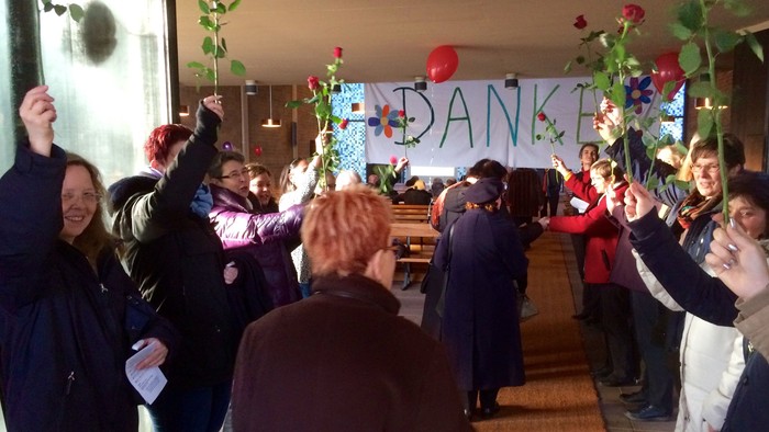 Ein Gruppe von Menschen feiert mit Luftballons und einem Dankeschön-Banner.