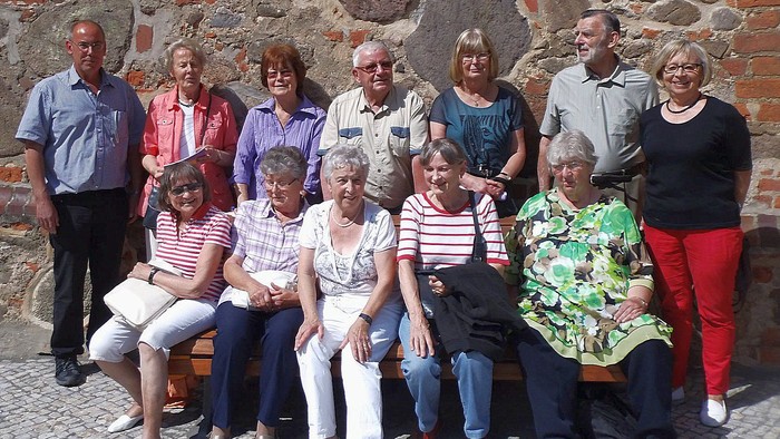Eine Gruppe von Menschen posiert vor einer Steinmauer