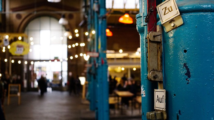 Blauer Tür mit Auf- und Zu-Schildern in einem belebten Markt