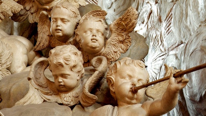 Engelsköpfe aus Stein, einer spielt Flöte