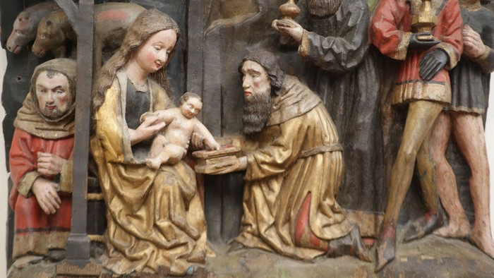 Die Holzskulptur zeigt eine religiöse Szene mit Maria, Josef und dem neugeborenen Jesus.