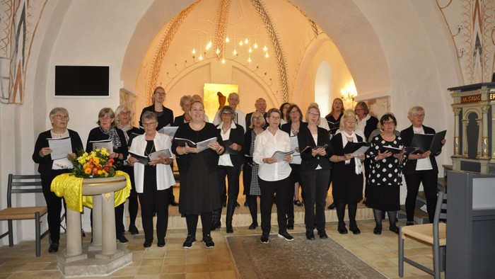 En kor sang i kirke med høje buevægge og lysende lys.