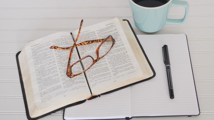En bog, en blikstift og en blå tektug på et hvidt bord