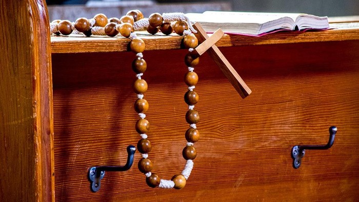 Holzperlenkette und Kreuz auf Holzregal