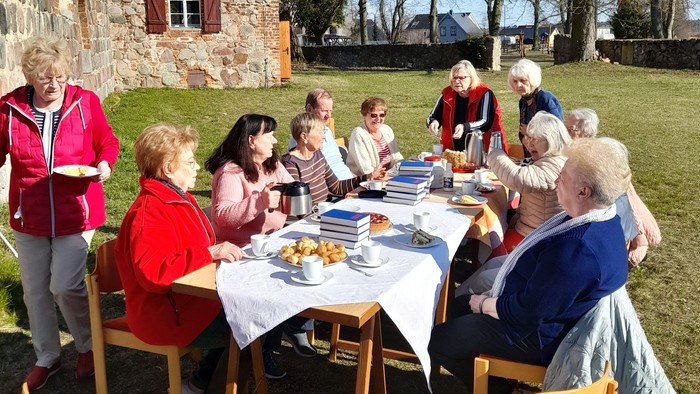 Eine Gruppe von Menschen sitzt an einem Tisch im Freien und isst.