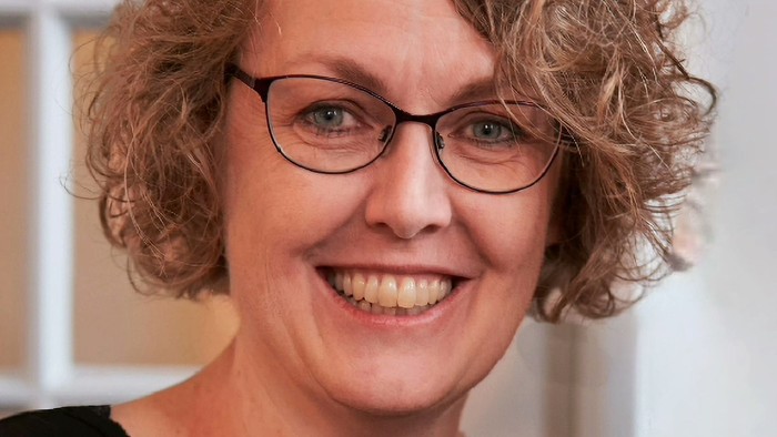 Kvinde, krøllet hår og briller - smiler