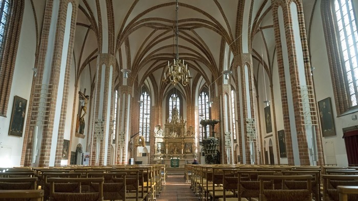 Innenraum einer gotischen Kirche mit hohen Säulen und einem Altarraum.