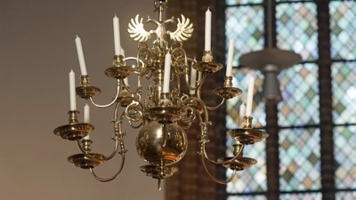 Ein Kronleuchter mit weißen Kerzen vor einem buntglasfenster