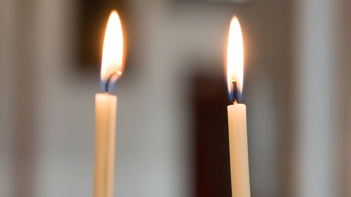 Zwei brennende Kerzen vor unscharfem Hintergrund