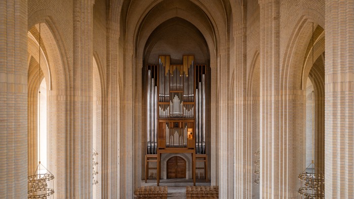 Indre del af en stor kirke med orgel og træbænke.