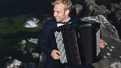 Mand der spiller harmonika nær vandet.