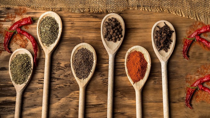 Verschiedene Gewürze in Holzlöffeln auf Holzoberfläche