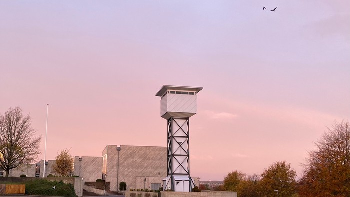 En industribygning med en høj tårnagtig struktur og en fugl i himlen