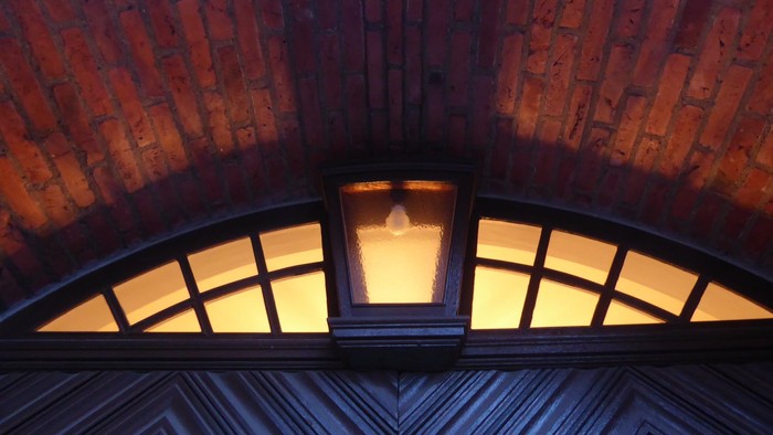 En lyset vindueskarm med gule glimmer under en mur af røde teglsten.