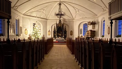 Indre del af kirke med høje vægge og hængende lygter.