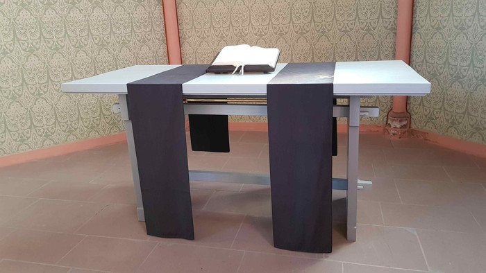 Moderner L-förmiger Schreibtisch mit einem offenen Buch auf der Oberfläche in einem dekorierten Raum.