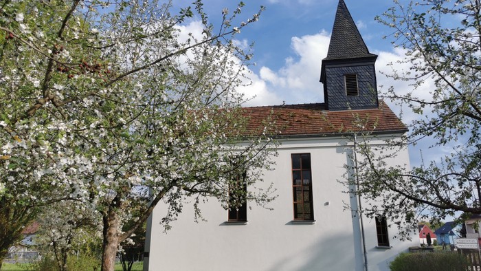 Weiße Kirche mit Turm und blühendem Baum davor