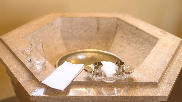 In der Mitte einer steinernen Schale stehen eine goldene Schale, ein Glas und ein weißes Stück Papier