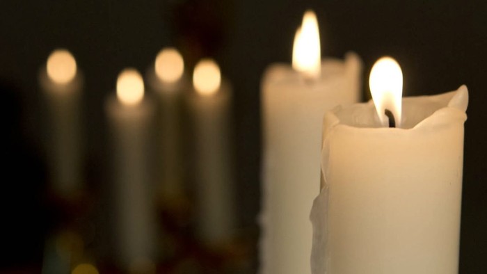 Mehrere brennende Kerzen in einer Reihe, unscharfe Hintergrundbeleuchtung