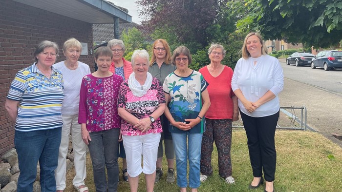 Eine Gruppe von Frauen posiert vor einem Backsteingebäude und Bäumen