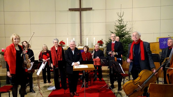 Ein Kirchenchor proben mit Musikern und Notenständern vor einem Kreuz und Weihnachtsbaum