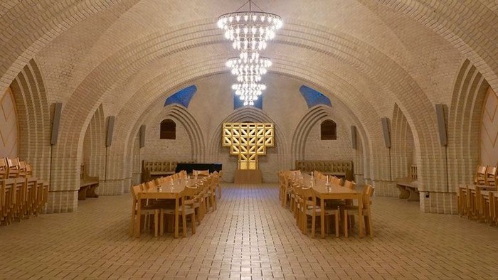 Stor underjordisk spisesal med buegange og høje belysninger.