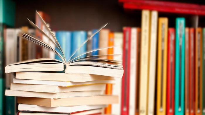 En stabel bøger på et skønsmør, med en blå bog på toppen.