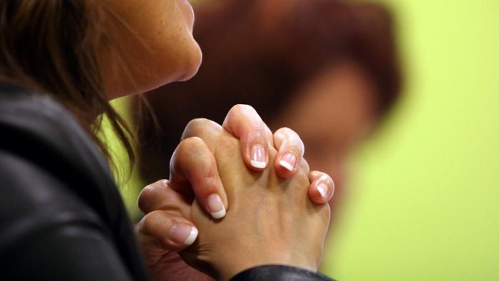 En person med sammenflettede hænder i bøn.