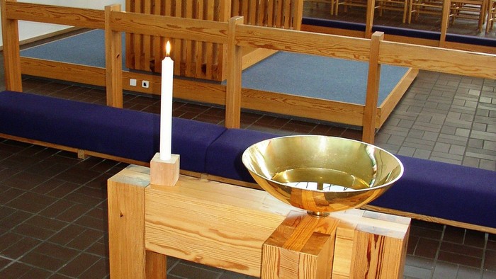 En lille bord med lysstake og vas i kirke.