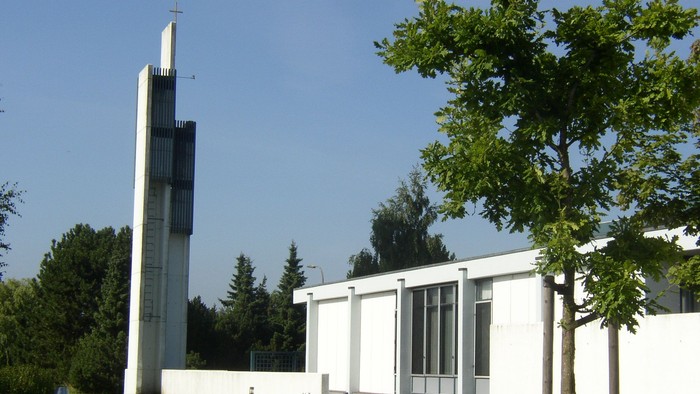 Hvid kirke med høj tårn og grønne træer