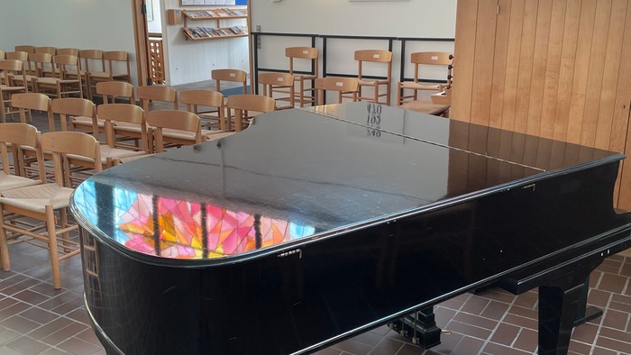 Sorte fløjtepiano i restaurant med farverige vinduesglas.