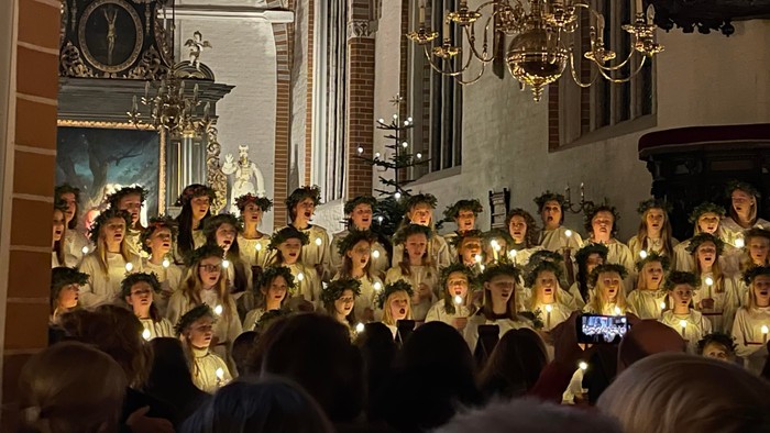 En kirke med en stor kor, der synger med lysede lys.