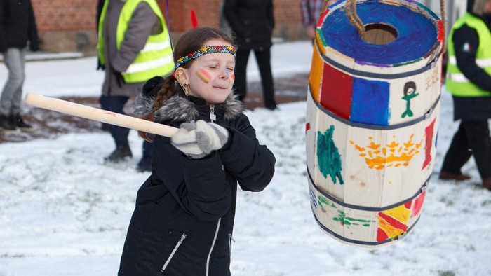 Pigen slår på en farverigt tønde i sneen.