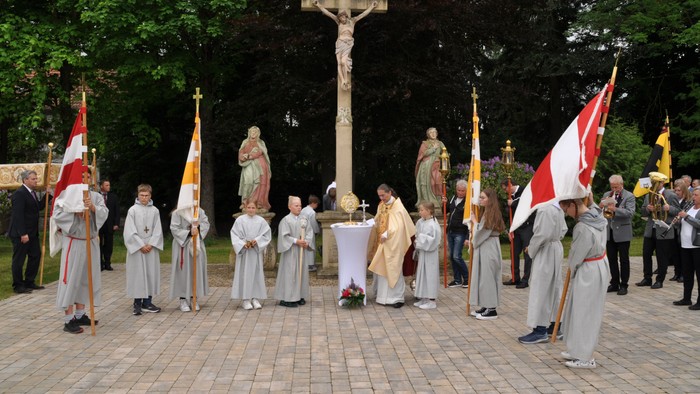 Religiöse Prozession mit Priestern und Flaggen vor Kreuz