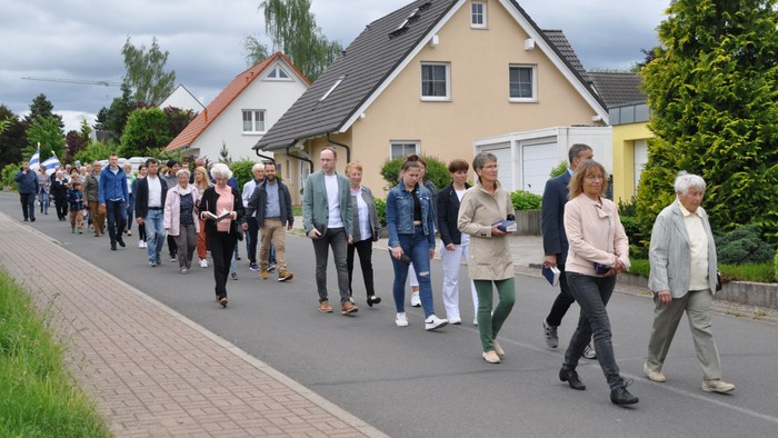Eine Gruppe von Menschen geht eine Straße entlang vor Häusern
