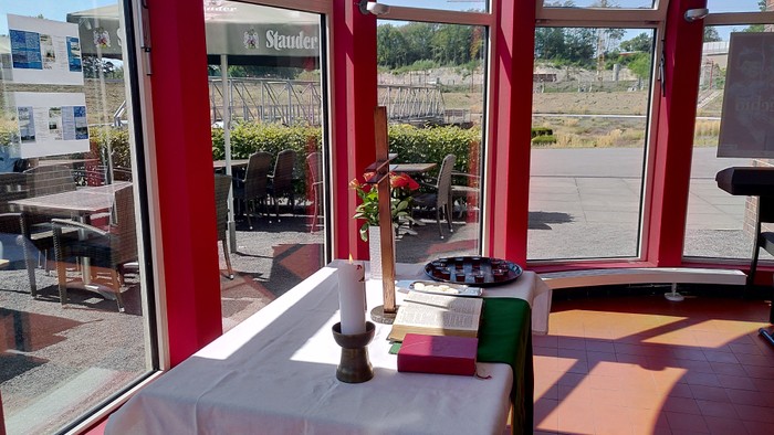 Ein Tisch mit weißer Decke darauf ein Buch und eine angezündete Kerze