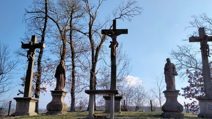 Ein Friedhof mit mehreren Kreuzen und einer Statue unter Bäumen