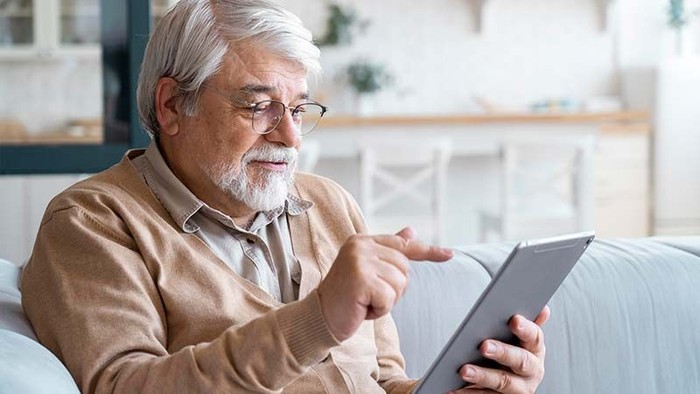 Alter Mann liest auf Tablet