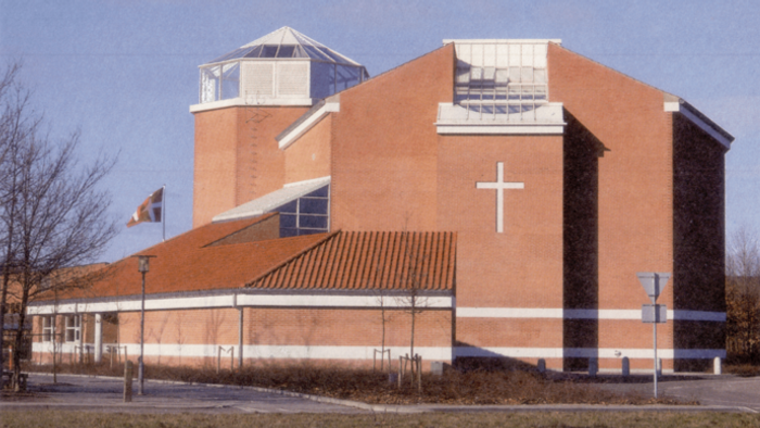 En stor, rød kirke med et stort kors på fasaden og en tårnagtig struktur på taket