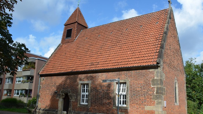 Kleine Backsteinkirche mit rotem Dach und Glockenturm.