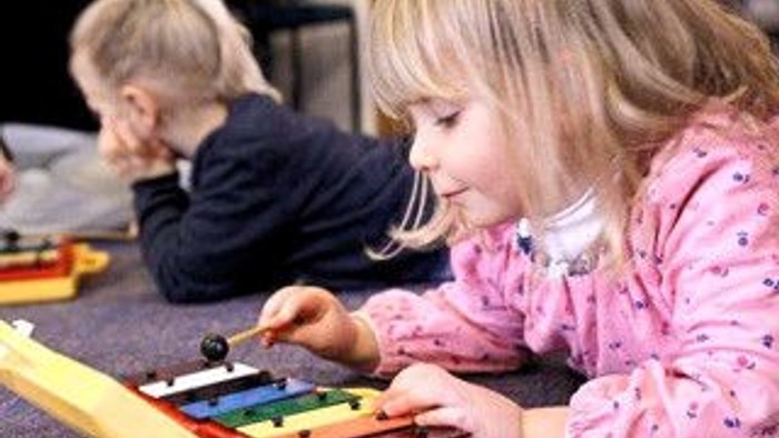 To børn spiller med legetøj på guldtæppe.