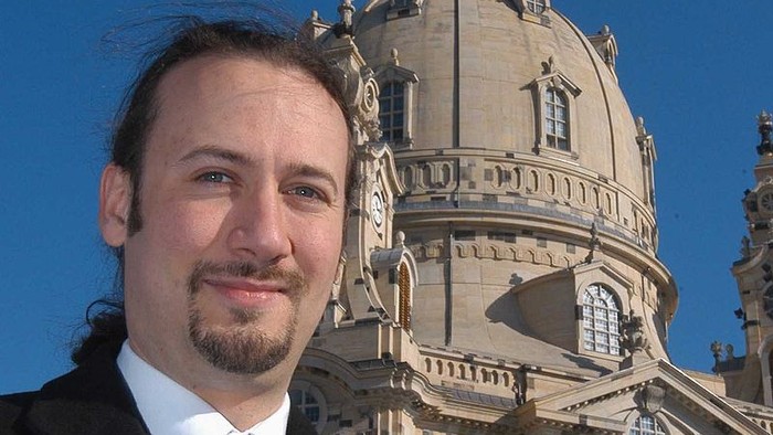 Mann in Anzug vor großer Kuppelkirche