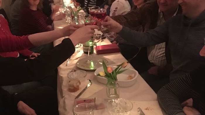 Eine Gruppe von Menschen sitzt an einem Tisch und feiert, mit Kerzen und Gläsern