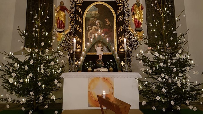 Weihnachtsdekoration in der Kirche mit Krippenszene und Tannenbäumen
