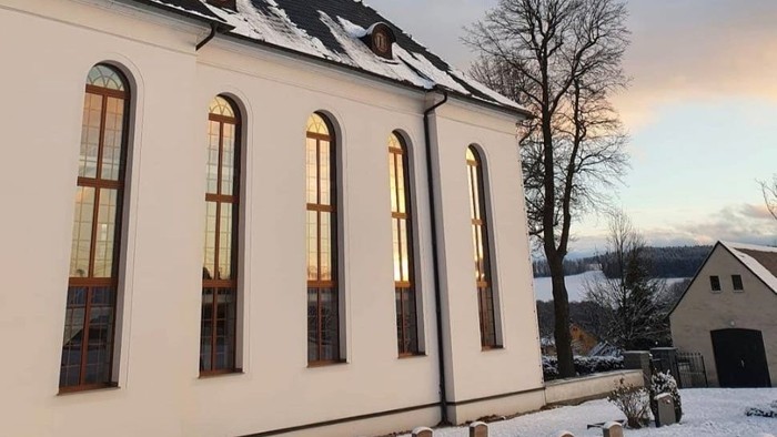 Weiße Kirche im Schnee mit hohem Turm und blauen Himmel