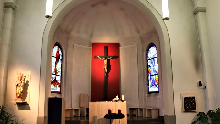 Innenraum einer Kirche mit Kreuz und Buntglasfenstern