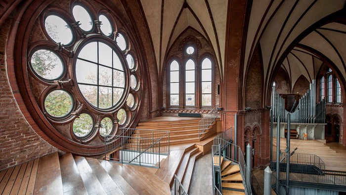 Großes Kirchenfenster in einem historischen Gebäude mit Treppen und Orgel