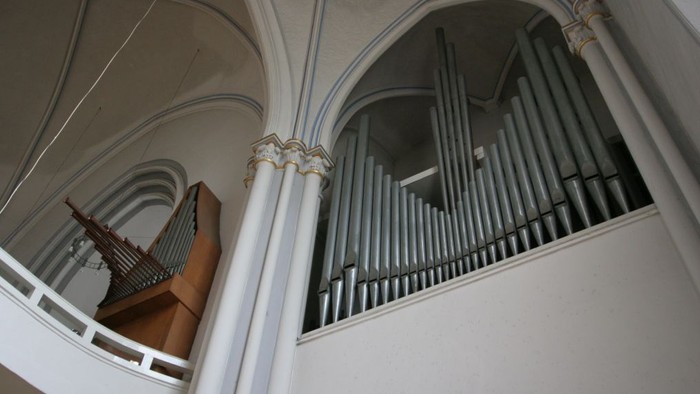 Ein Kirchenorgel mit weißen Pfeifen und verzierten Säulen.