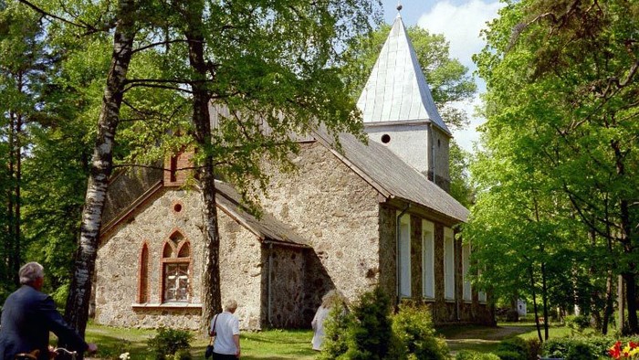 Kirchengemeinde trifft sich vor alter Kirche im Wald.