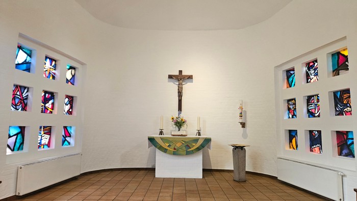 Kleine Kapelle mit farbenfrohen Fenstern und einem Altar mit Kruzifix